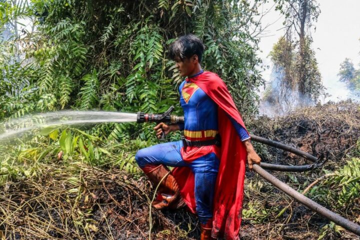 Un adolescent en Superman combat les incendies à Bornéo, mettant en lumière la crise écologique en Indonésie